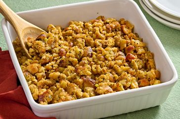 A white baking dish with stovetop stuffing and a wooden spoon