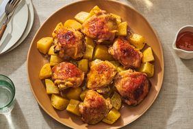 Roasted chicken thighs with potatoes served on a brown plate.